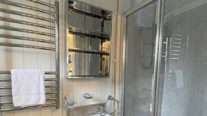 A compact bathroom with a toilet, sink, and glass-enclosed shower. - Shepherds  View -  a tiny home that sleeps 2 guests  in 1 bedroom (Glenshee)