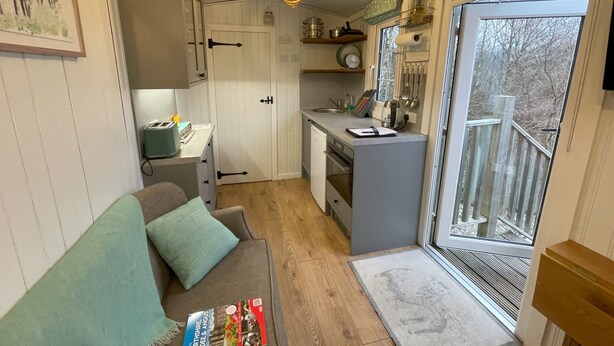 A compact kitchen with a dining area, a sofa, and a view of the outdoors. - Shepherds  View -  a tiny home that sleeps 2 guests  in 1 bedroom (Glenshee)
