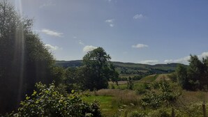 A rural landscape with rolling hills, scattered trees, and a clear sky. - Shepherds  View -  a tiny home that sleeps 2 guests  in 1 bedroom (Glenshee)