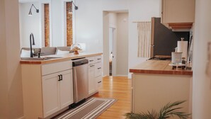 A modern kitchen with wooden flooring, white cabinetry, and a built-in dishwasher. - Charming 2-bedroom apartment with AC, WiFi in lovely Mifflinburg (Mifflinburg)