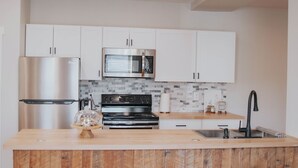A modern kitchen with white cabinets, stainless steel appliances, a wooden island, and a tiled backsplash. - Charming 2-bedroom apartment with AC, WiFi in lovely Mifflinburg (Mifflinburg)