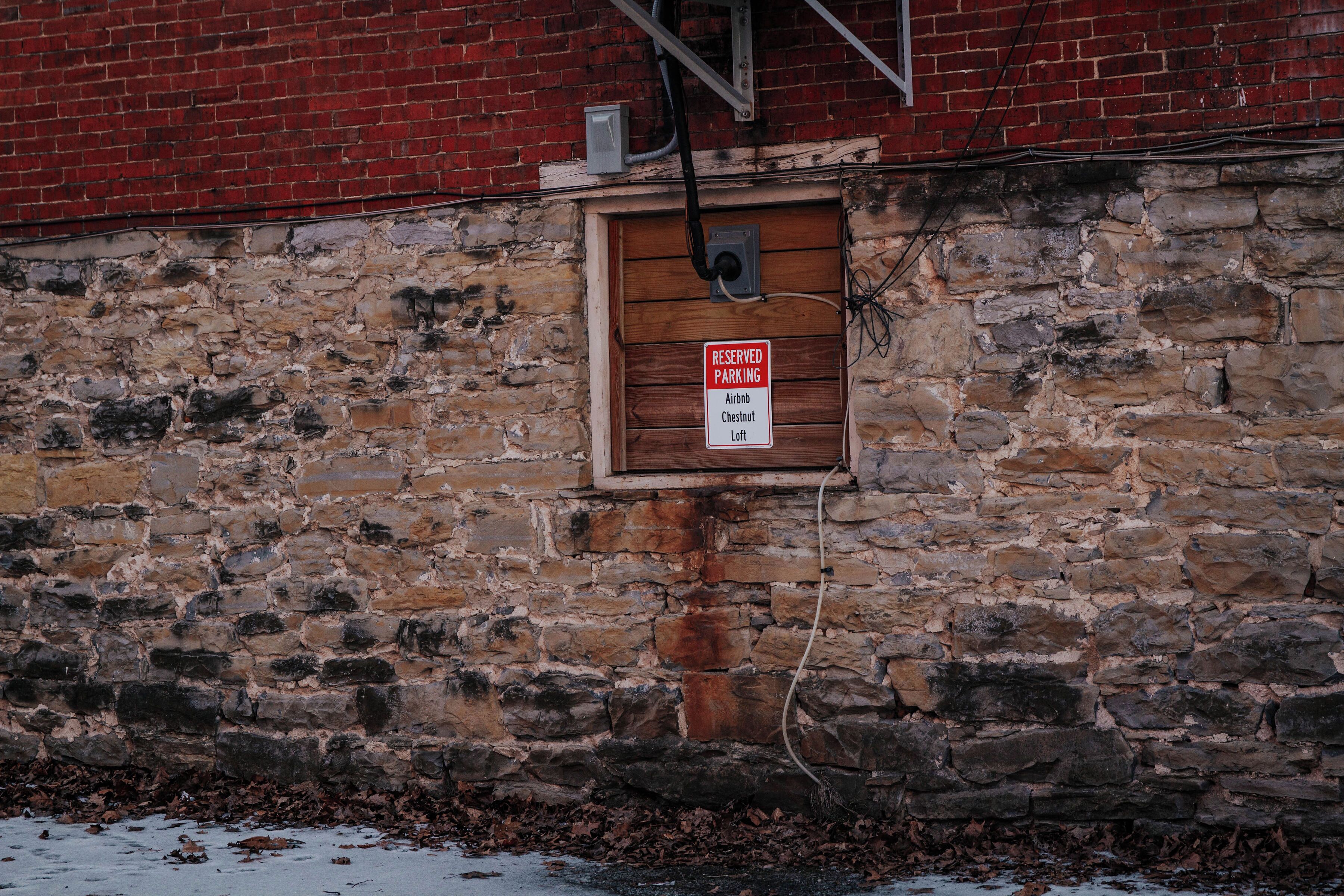 Eine Steinsäule mit einer Holztür und einem Schild, das reservierte Parkplätze für Airbnb, Chestnut und Loft anzeigt.