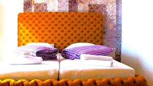 Una cama doble con cabecera capitonada, dos almohadas y una manta doblada con cuidado.