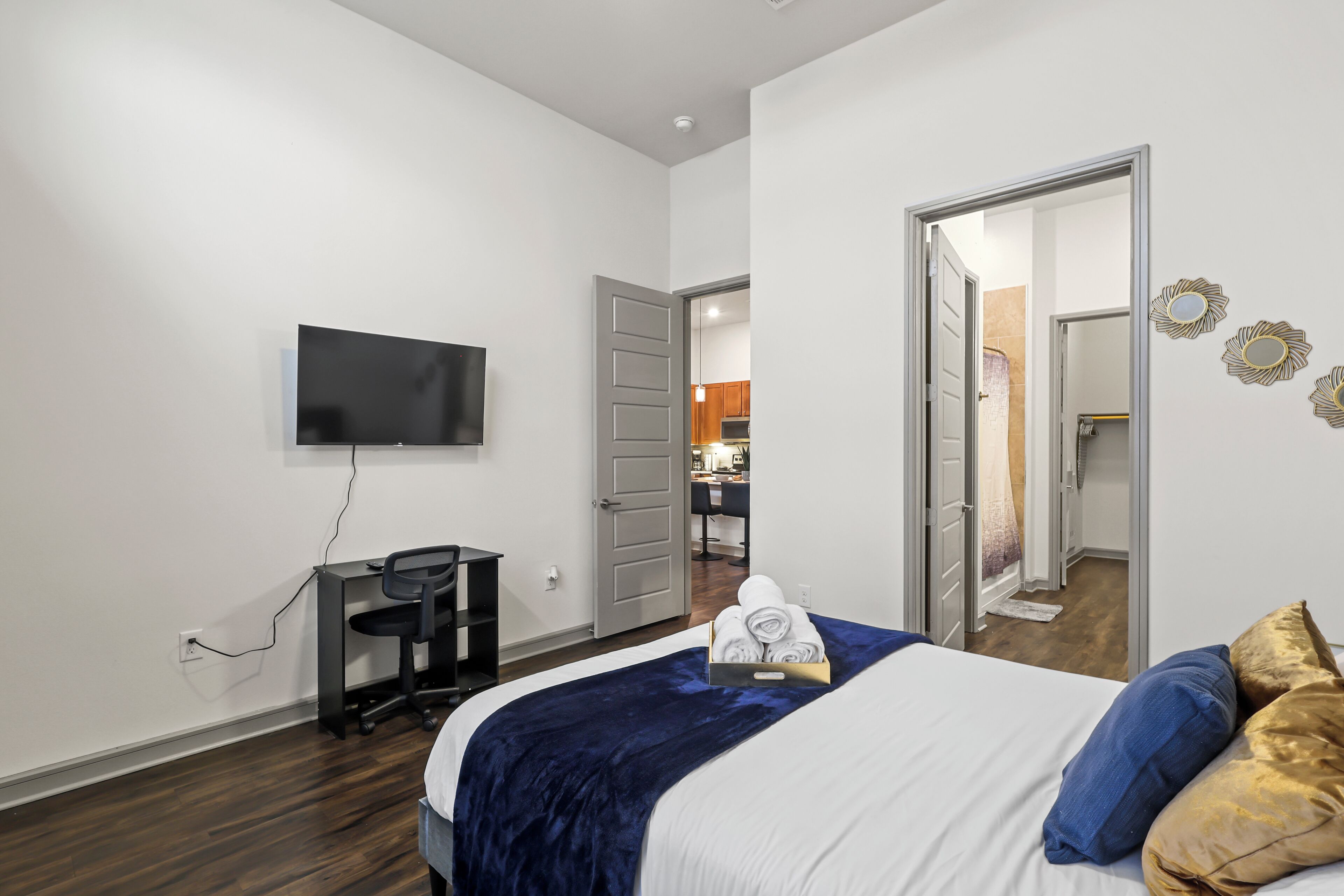 Een hotelkamer met een bed, een bureau, een televisie en een badkamer, zichtbaar door een open deur.