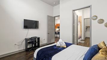 Een hotelkamer met een bed, een bureau, een televisie en een badkamer, zichtbaar door een open deur.
