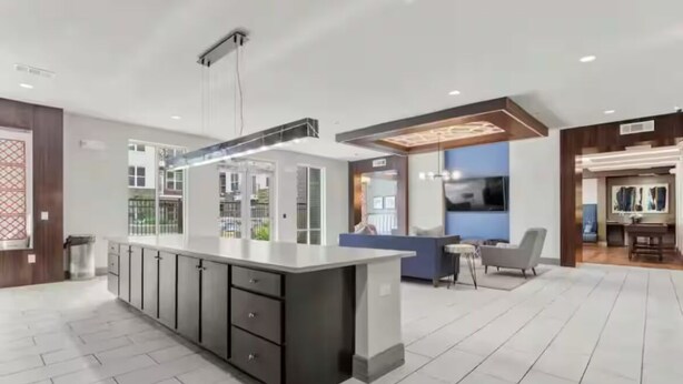 A modern kitchen with a central island, built-in cabinets, and a dining area with a blue accent wall.