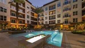 A multi-story hotel with a central pool, outdoor seating, and palm trees.