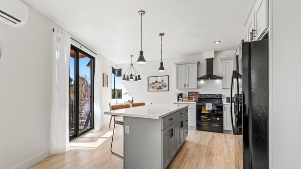 A modern kitchen with a central island, grey cabinets, and a black refrigerator. - Quiet getaway w/2 kings, 3 beds pet friendly (Flagstaff)