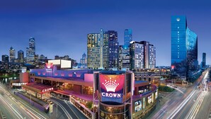 A hotel with a prominent 'Crown' sign, surrounded by a cityscape with modern high-rise buildings.