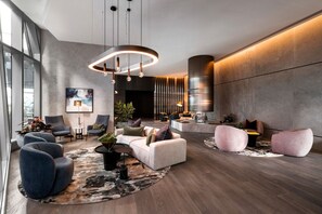 Relax in our stylish lobby, featuring a cozy seating area with a sofa and armchairs, a unique art piece, and a lush potted plant.