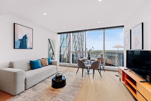 Relax in a spacious living room with a city view, comfortable sofa, dining area, and flat-screen TV.