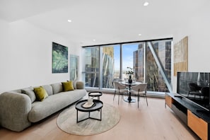 Relax in a spacious living room with a sofa, coffee table, and dining area, offering a city view.