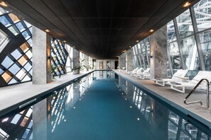 Relax by the elongated pool surrounded by large windows and lounge chairs.