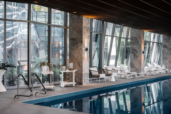 Relax by the pool surrounded by lush greenery and minimalist decor.