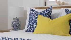 A bed with white and blue patterned bedding, a yellow pillow, and a blue and white patterned pillow.
