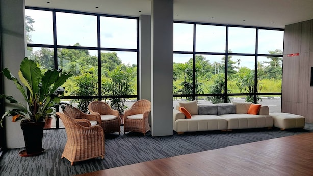 A spacious room with large windows, wicker furniture, a beige sofa, and a wooden table. - ROXY HOTEL MALIHAH (Kuching)
