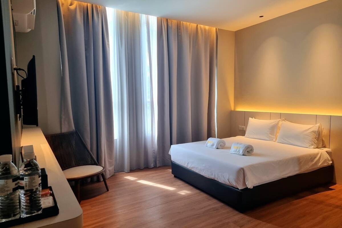 Hotellihuone, jossa on sänky, työpöytä, tuoli ja televisio.