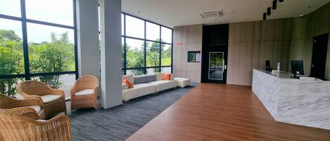 A spacious lobby with large windows, a reception desk, and seating area.