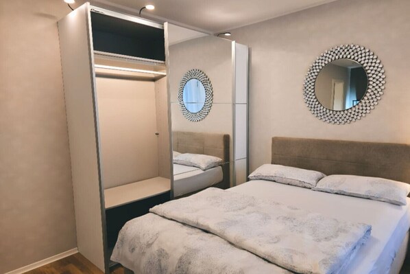 Relax in this inviting space with a comfortable bed, a stylish wardrobe, and two wall-mounted mirrors.