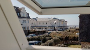 A coastal building with a balcony, a parking area, and a view of the sea. - Nordseezauber - North Sea magic - Holiday apartment near the beach with sea view in (Wenningstedt-Braderup (Sylt))