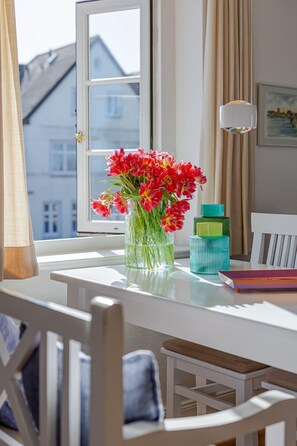A table with a vase of flowers, a lamp, and a book.