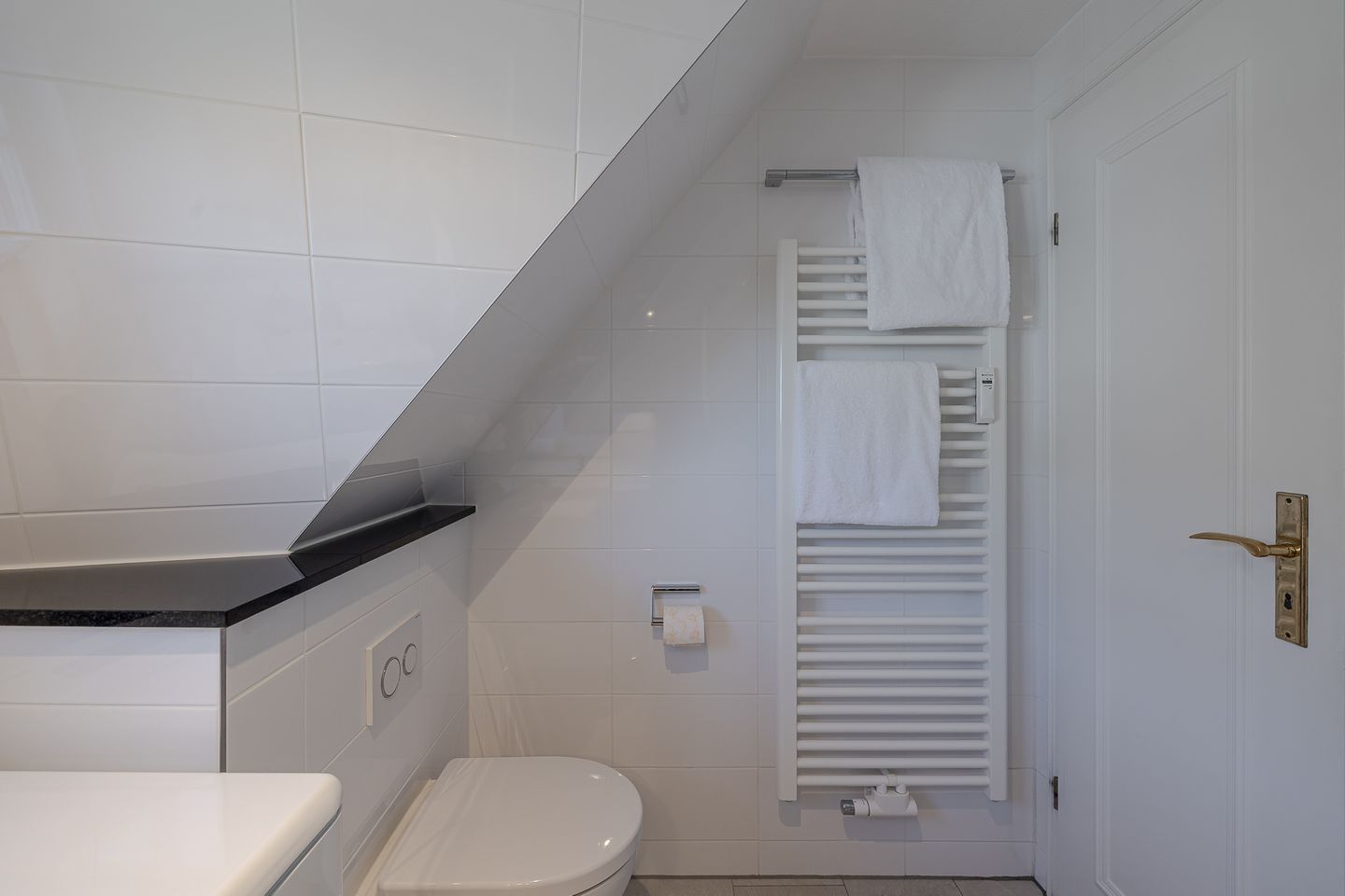 Ein Badezimmer mit Toilette, Waschbecken, Handtuchhalter und Heizkörper.
