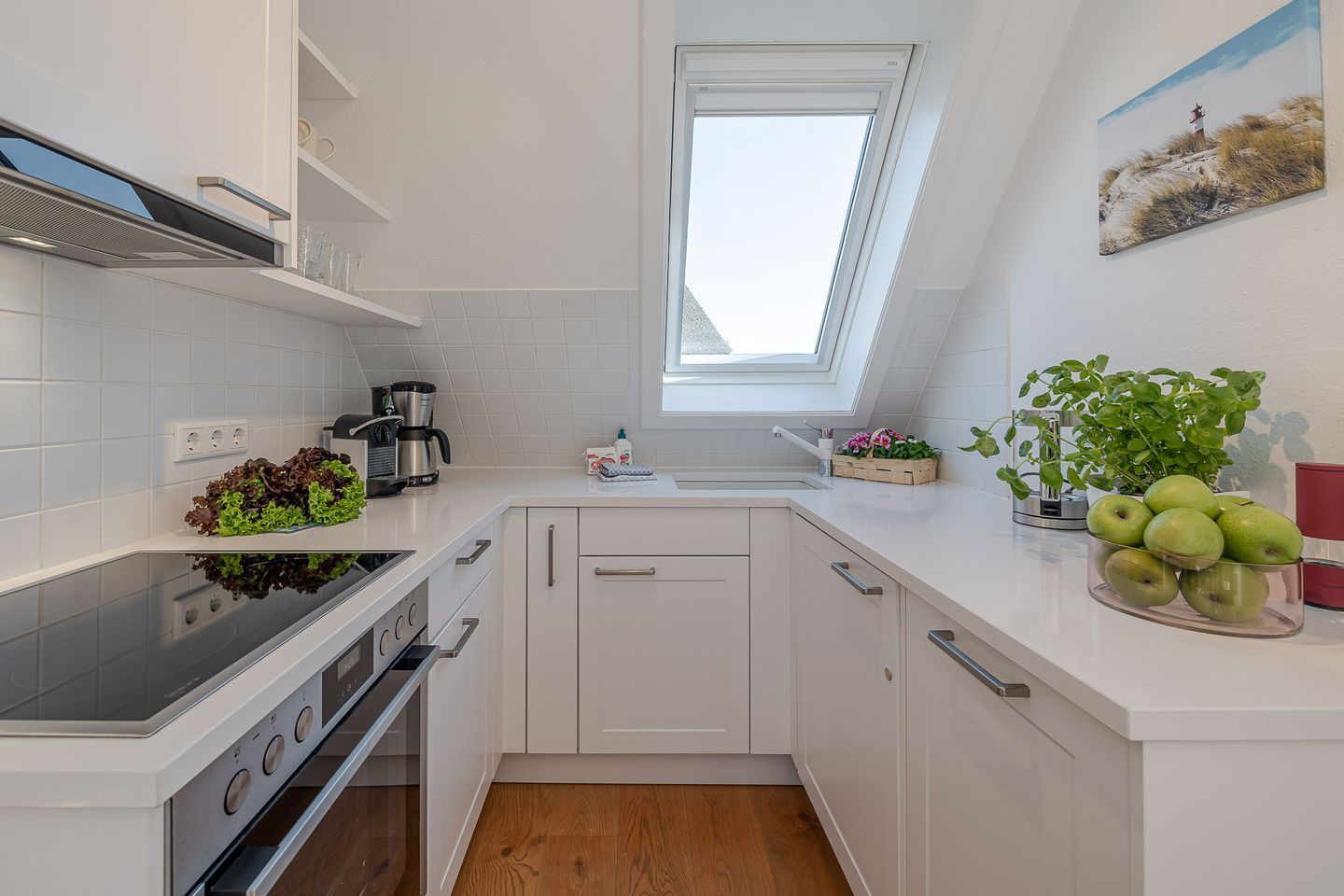 A compact kitchen with white cabinetry, a built-in oven, a coffee maker, and a window above the sink.