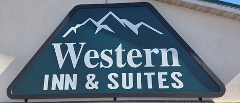 En skylt för Western Inn & Suites med en bild av ett berg.