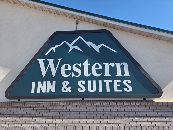 A sign for Western Inn & Suites with a mountain graphic. - New Western Inn & Suites (Fillmore)