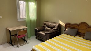 Ein Schlafzimmer mit Bett, Schreibtisch, Stuhl und einem Fenster mit Vorhängen.