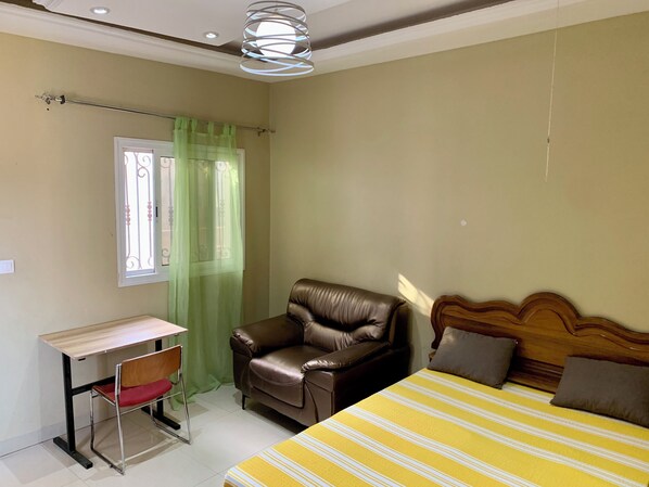 Un dormitorio con cama, escritorio y sillón de cuero.