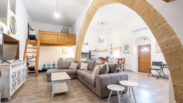 A spacious living area with a large sofa, a dining table, and a kitchen in the background. - Amalia's Traditional Home In Paradisi (Paradeisi)