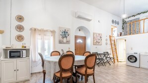 A dining area with a round table, chairs, and a microwave on a cabinet. - Amalia's Traditional Home In Paradisi (Paradeisi)