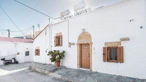 A white building with a stone staircase, a wooden door, and a potted plant. - Amalia's Traditional Home In Paradisi (Paradeisi)