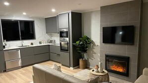 A modern kitchen with grey cabinets, a built-in oven, and a large window. -  Cosy townhouse with picturesque lakeside views. (Jindabyne)