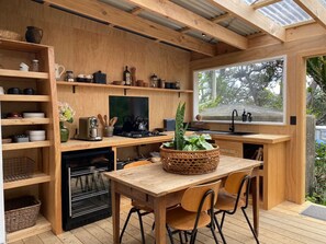 Eine kleine Küche mit Holzschränken, einem Esstisch und einem großen Fenster.