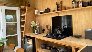 Una cucina compatta con piano cottura a gas, mensole in legno e diversi utensili da cucina.