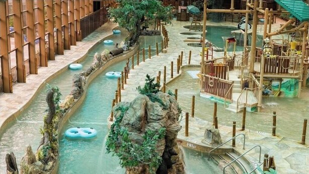 Un parc aquatique intérieur doté de nombreux toboggans, d’une formation rocheuse centrale et d’un espace de jeux avec diverses structures.