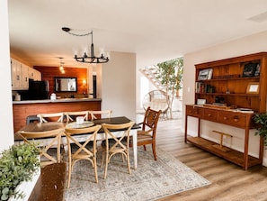 A cozy interior with a dining area, wooden furniture, a bookshelf, and a staircase leading to an outdoor area.