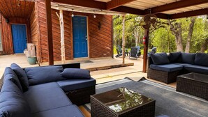 A covered outdoor seating area with a sofa and chairs, a wooden door, and a fan. - Private Retreat w/ Animals. Outdoor Fire pit/ BBQ (Cedar Creek)