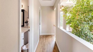 A narrow hallway with a wooden floor, a white door, and a window with a view of greenery. - Private Retreat w/ Animals. Outdoor Fire pit/ BBQ (Cedar Creek)