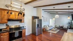 Una cocina con armarios de madera, electrodomésticos de acero inoxidable y una zona de comedor con sofá y mesa.
