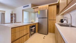 Una cocina moderna con armarios de madera, un refrigerador de acero inoxidable, un horno empotrado y un lavamanos con un grifo moderno.