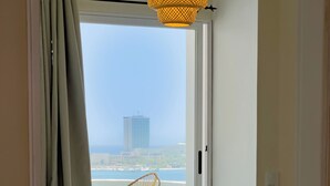 Una habitación con cama, una silla y vistas a un edificio y al agua.