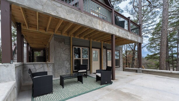 A covered outdoor seating area with stone walls, wooden beams, and a view of trees. - Away in the Woods~ Pinnacle, Wi-Fi (Little Rock)