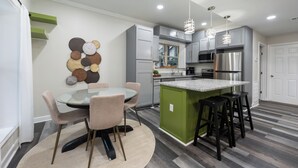 A modern kitchen with grey cabinets, a stainless steel refrigerator, and a round dining table with chairs. - Away in the Woods~ Pinnacle, Wi-Fi (Little Rock)