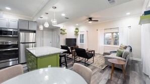 A modern kitchen with stainless steel appliances, a green island, and a dining area with a round table and chairs. - Away in the Woods~ Pinnacle, Wi-Fi (Little Rock)