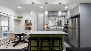 A modern kitchen with a central island, bar stools, and a dining area. - Away in the Woods~ Pinnacle, Wi-Fi (Little Rock)