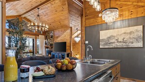 A kitchen with wooden beams, a chandelier, a sink, and a fruit bowl on the counter. - Spring Break for families in BR with Sauna, Hot tub, Firepit & amazing views (Blue Ridge)
