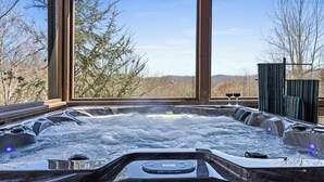 A hot tub with a control panel, surrounded by large windows offering a view of trees and hills. - Spring Break for families in BR with Sauna, Hot tub, Firepit & amazing views (Blue Ridge)